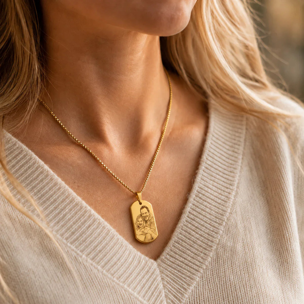 Plaque militaire dorée gravée portée en collier, pull beige
